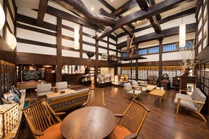 A spacious interior with high ceilings, exposed wooden beams, and a variety of seating arrangements including sofas and chairs. - Ryokan Asunaro (Takayama)