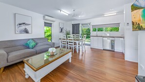 A modern living area with a sofa, dining table, and kitchen. - BIG4 Whitsunday Islands Holiday Park (Flametree)