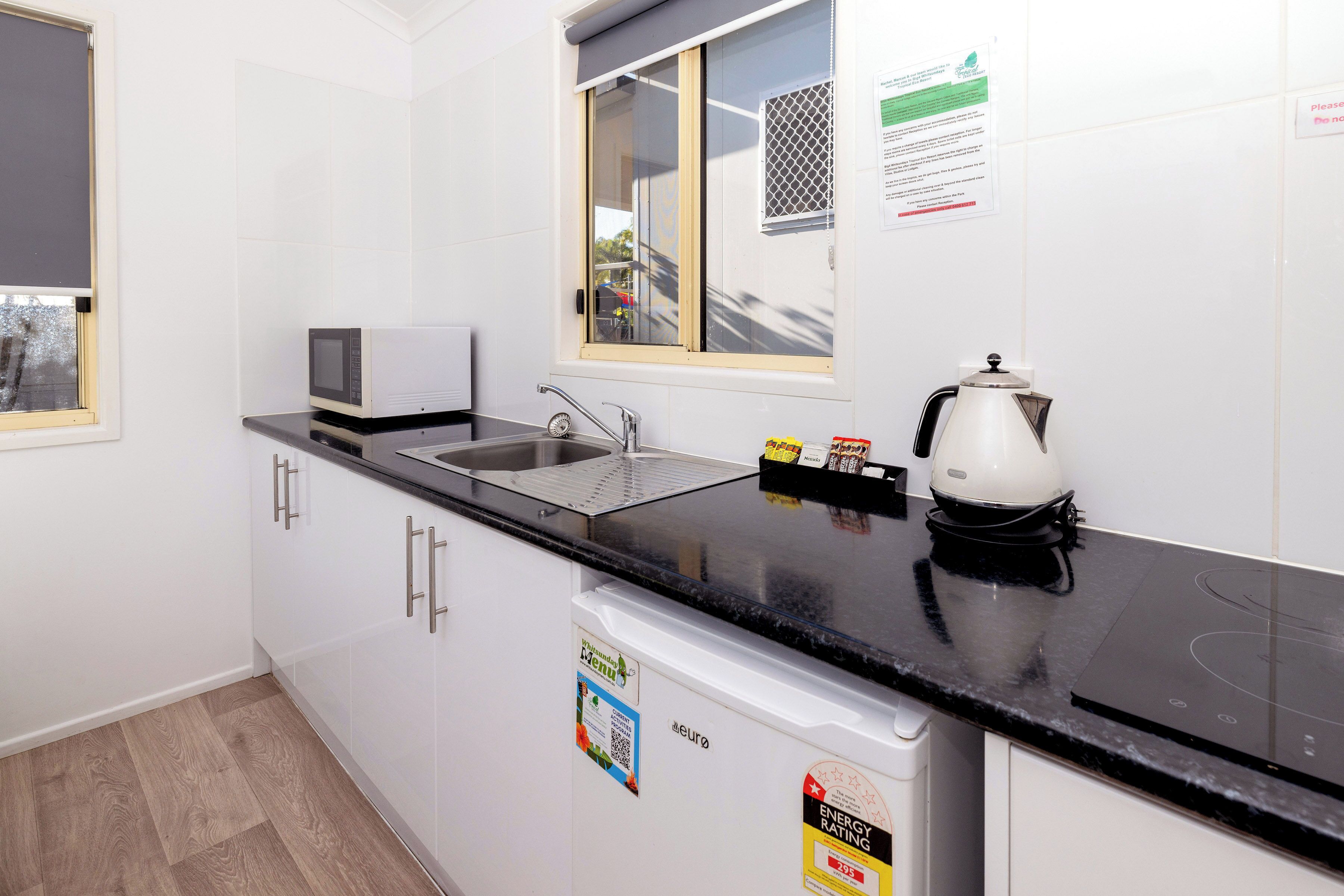 A modern kitchen with a black countertop, stainless steel sink, and a coffee maker.