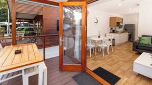 A modern kitchen with wooden cabinets, a refrigerator, and a dining area with a table and chairs. - BIG4 Whitsunday Islands Holiday Park (Flametree)