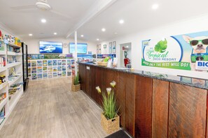Un área de recepción con un mostrador de madera, un televisor mostrando un crucero y un letrero del Tropical Eco Resort.