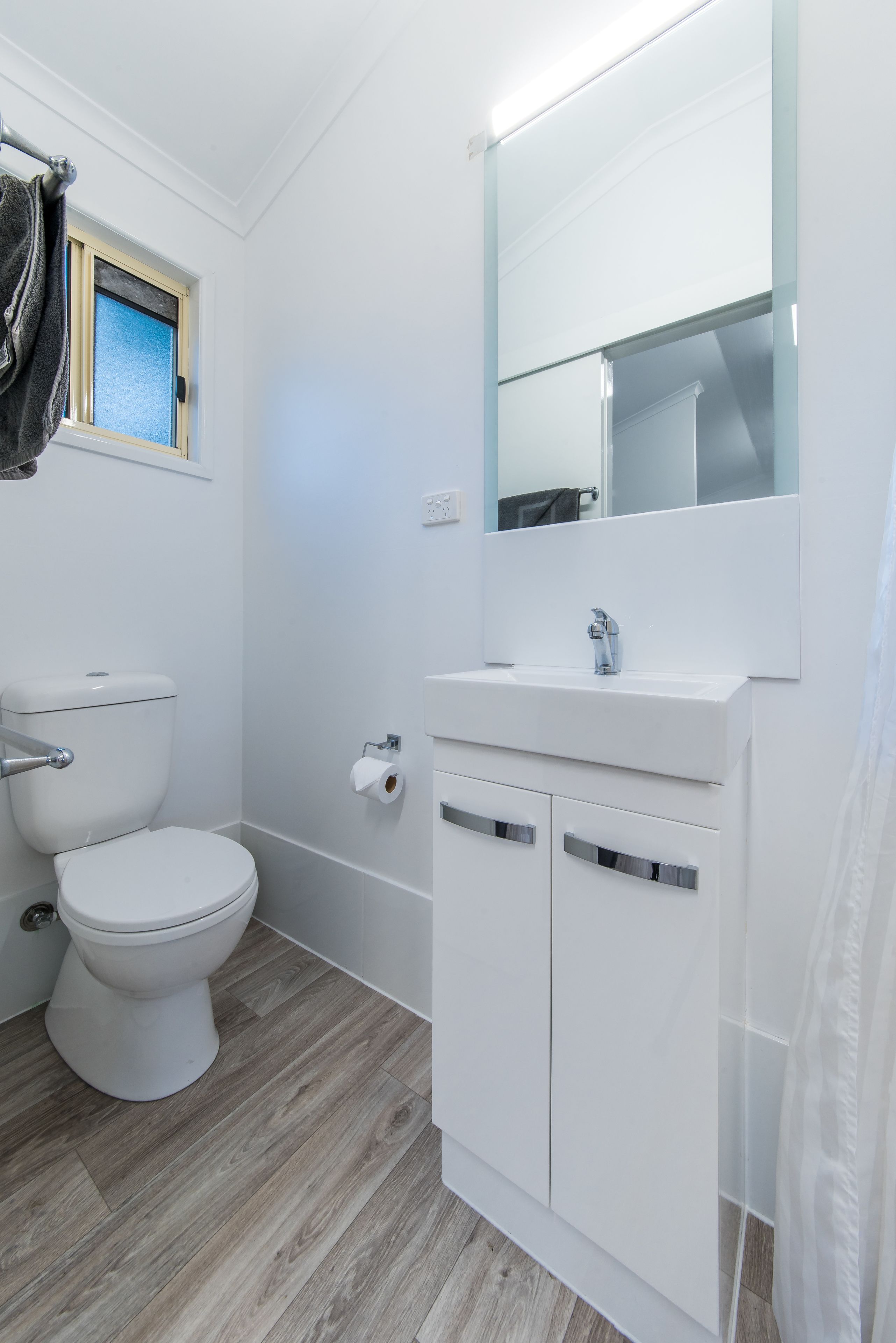A bathroom with a toilet, sink, and mirror.