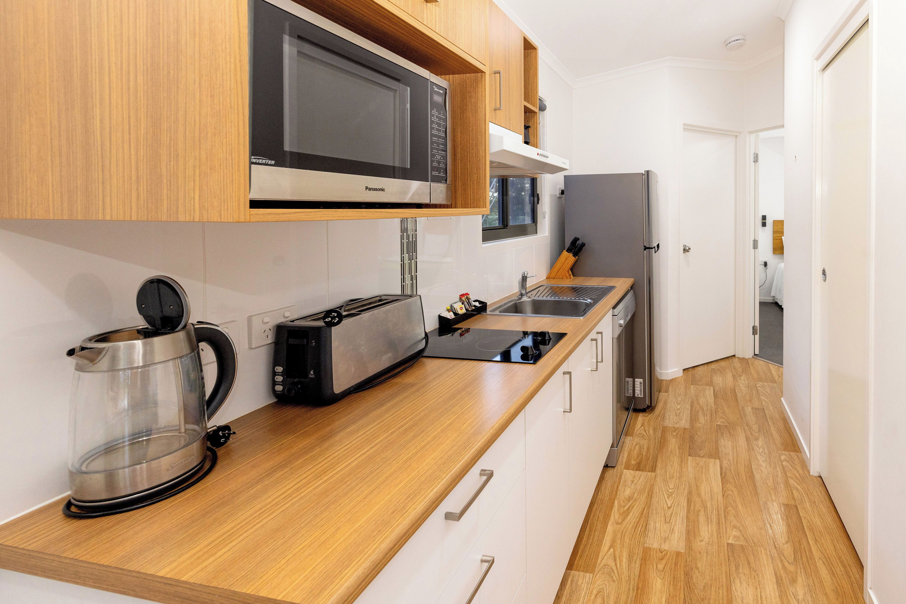 Une cuisine moderne dotée de meubles en bois, d’un four à micro-ondes, d’un grille-pain et d’une bouilloire.