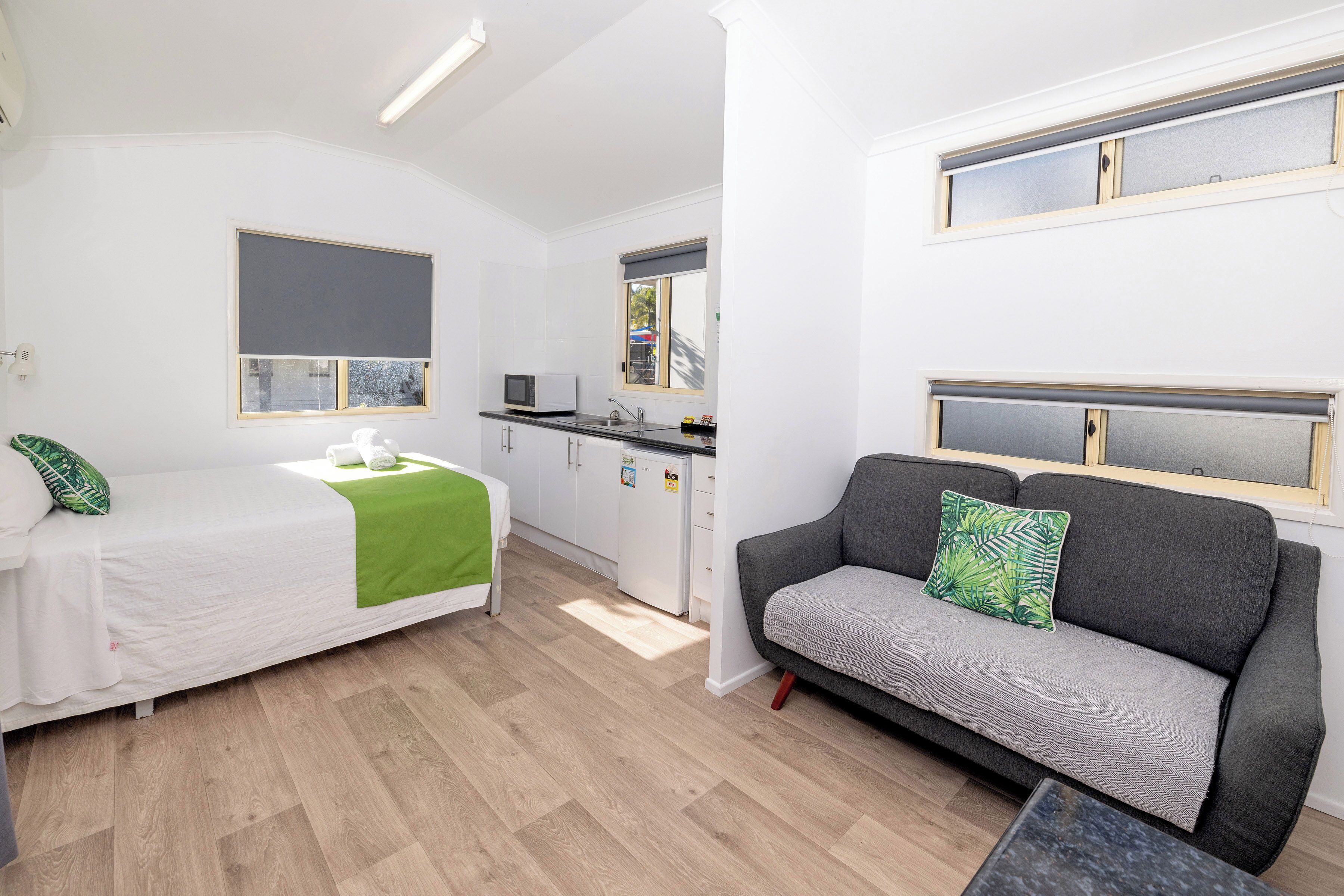 A compact living space with a bed, a sofa, a small kitchenette, and a dining area.