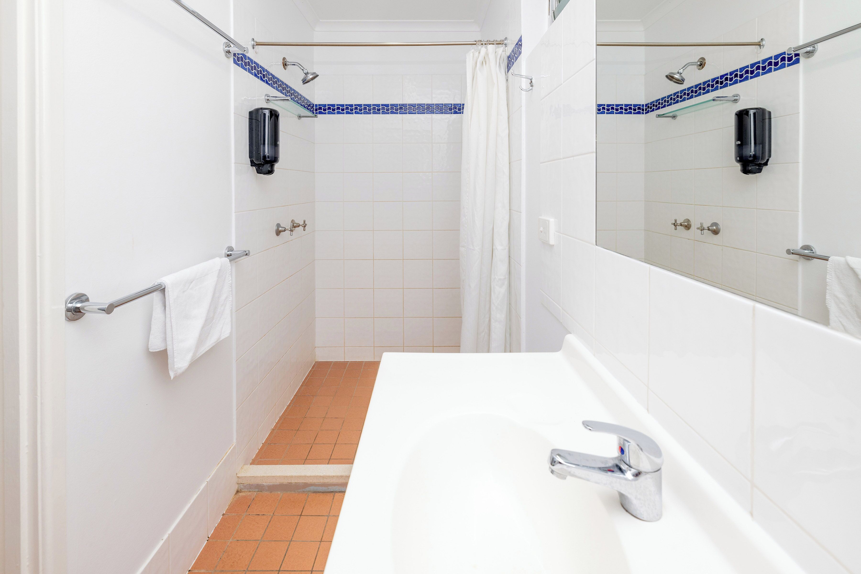 A bathroom with a white sink, a shower with a glass door, and a towel rack.