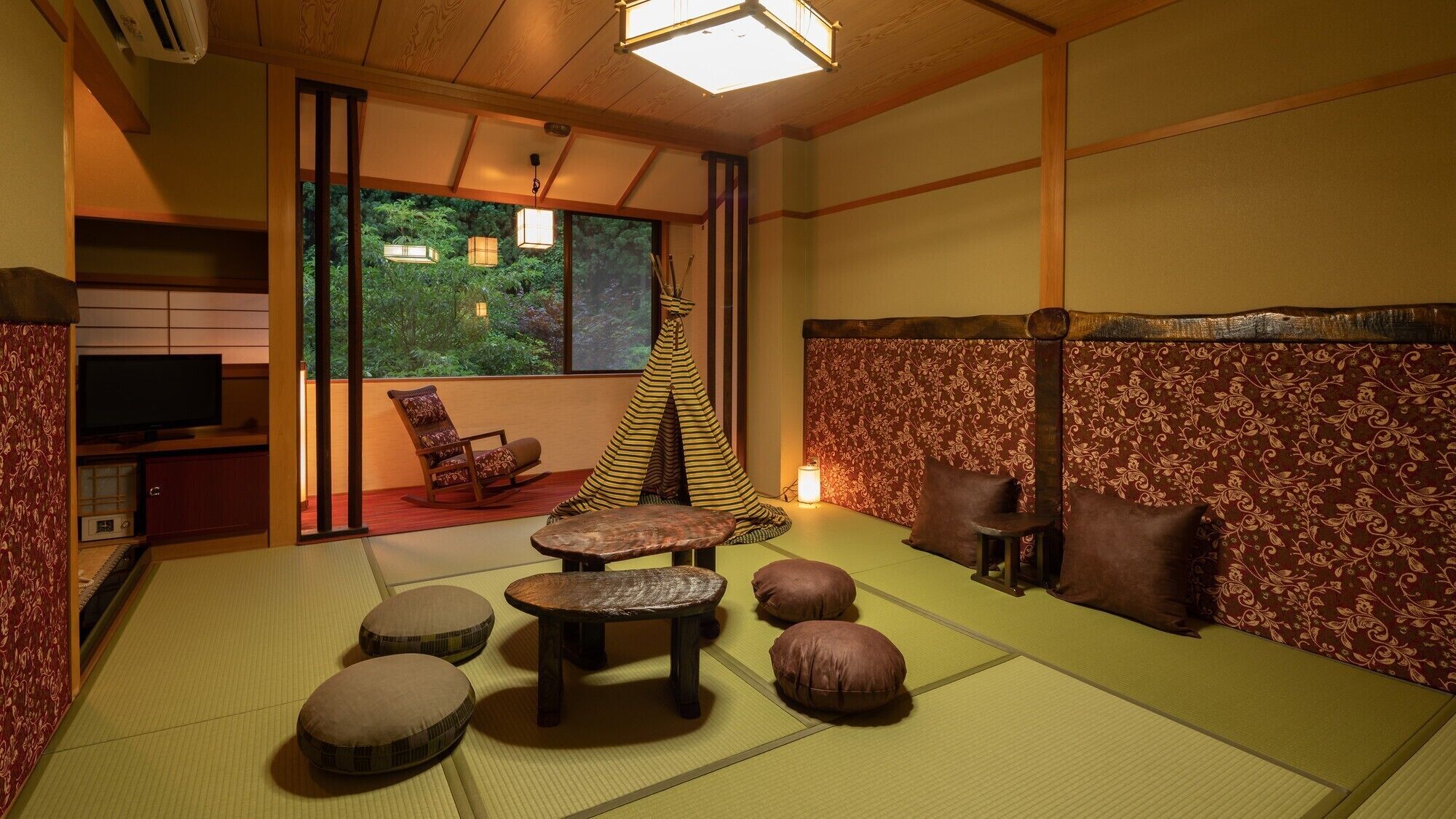 Una habitación japonesa tradicional con suelo de tatami, televisor, mecedora, una mesita y vistas a zonas verdes.