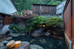 Un jardín japonés tradicional con un estanque de carpas, estructuras de madera y una pequeña cascada.