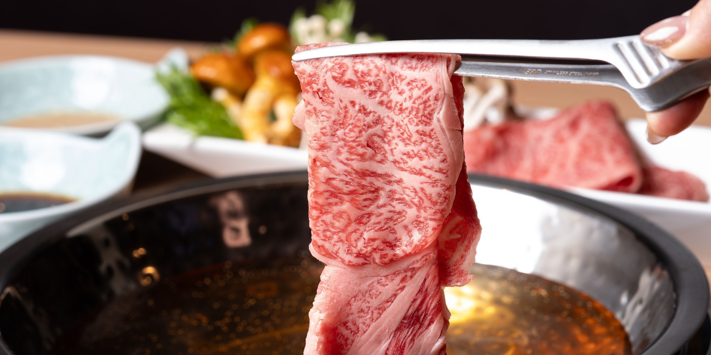 A close-up of a person holding a piece of meat with a fork.