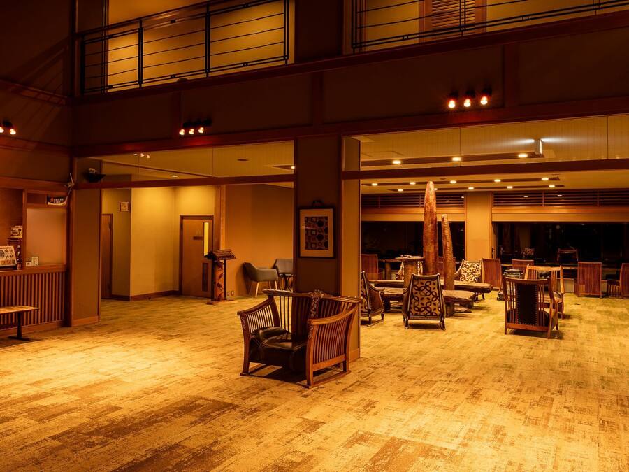 A spacious lobby with a high ceiling, wooden flooring, and multiple seating areas.
