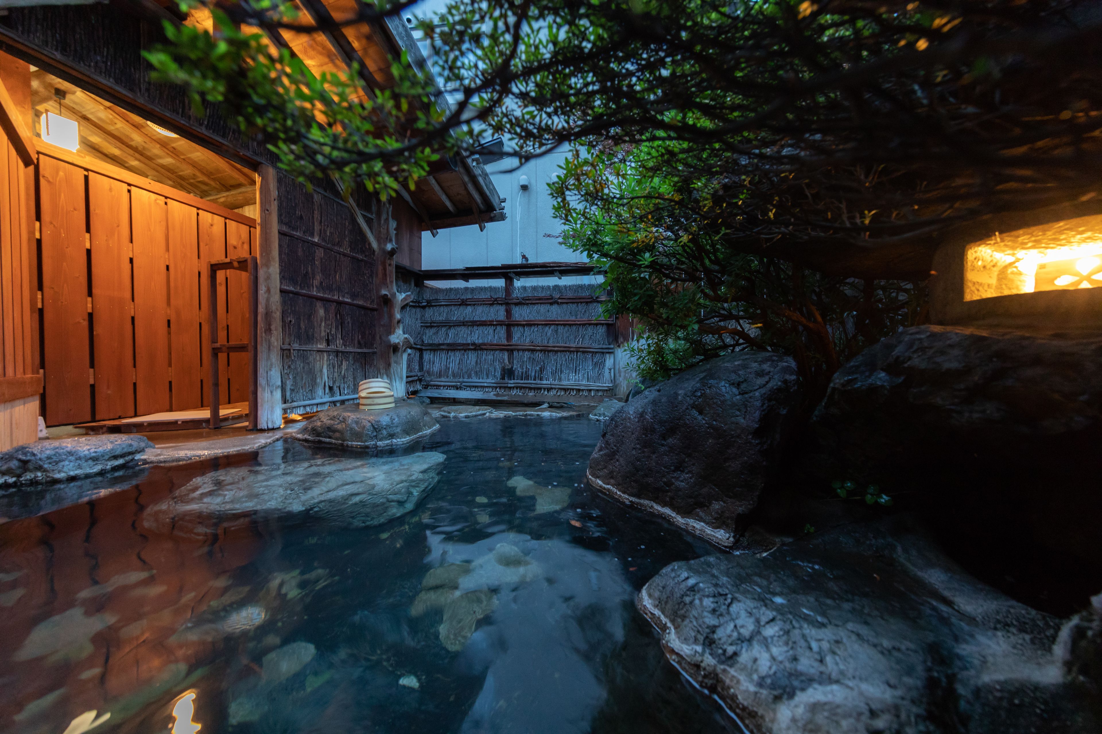 Il s’agit d’un bâtiment japonais traditionnel, avec une façade en bois, un chemin de pierre et un petit étang agrémenté de rochers.