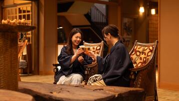 Two people sitting on ornate chairs in a warmly lit room with traditional decor.