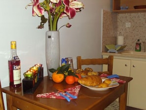 Una mesa de comedor con comida, una botella y un florero con flores.