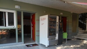 A reception area with a vending machine, a green chair, and a tiled floor. - Hotel Vasilis (Nafplio)