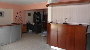A kitchen with a wooden counter, a refrigerator, and a dining area with a table and chairs. - Hotel Vasilis (Nafplio)