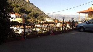 A parking area with a car, a fence, and buildings in the background. - Hotel Vasilis (Nafplio)