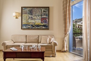 Una sala de estar con un sofá color beige, una mesa de centro, un cuadro y vistas por una ventana.