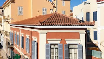 Ein traditionelles mediterranes Gebäude mit einem Ziegeldach, einem Balkon mit schmiedeeisernem Geländer und einer kleinen Sitzterrasse mit Tisch und Stühlen.