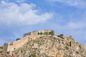 A historic stone fortress on a hill with arched windows and a flat roof.