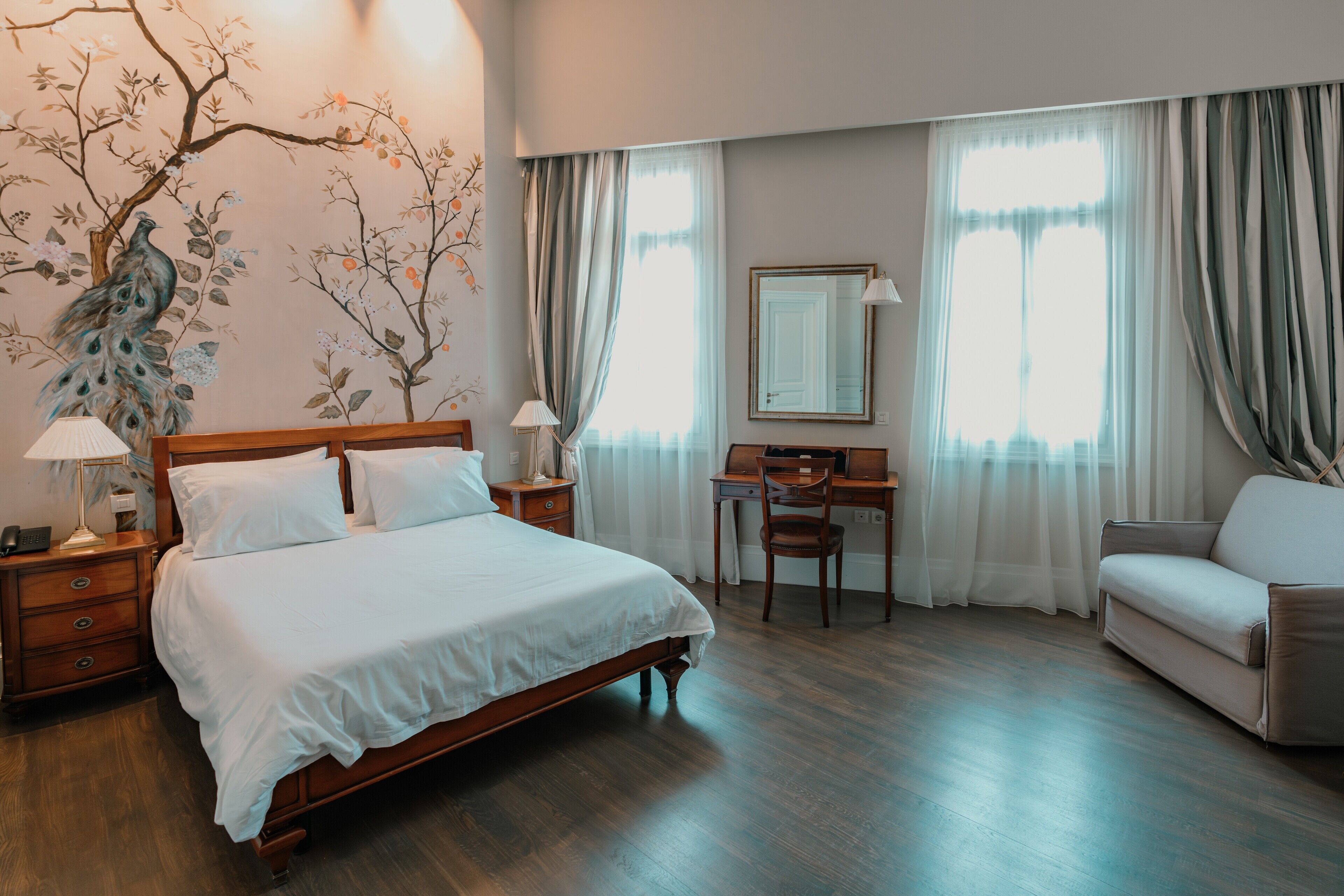 Une chambre d’hôtel avec un lit en bois, un bureau, une chaise et un canapé.