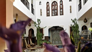 Ein Innenhof mit einem gemusterten Boden, einer Sitzgruppe in der Mitte und einer Wand mit einer Tür.