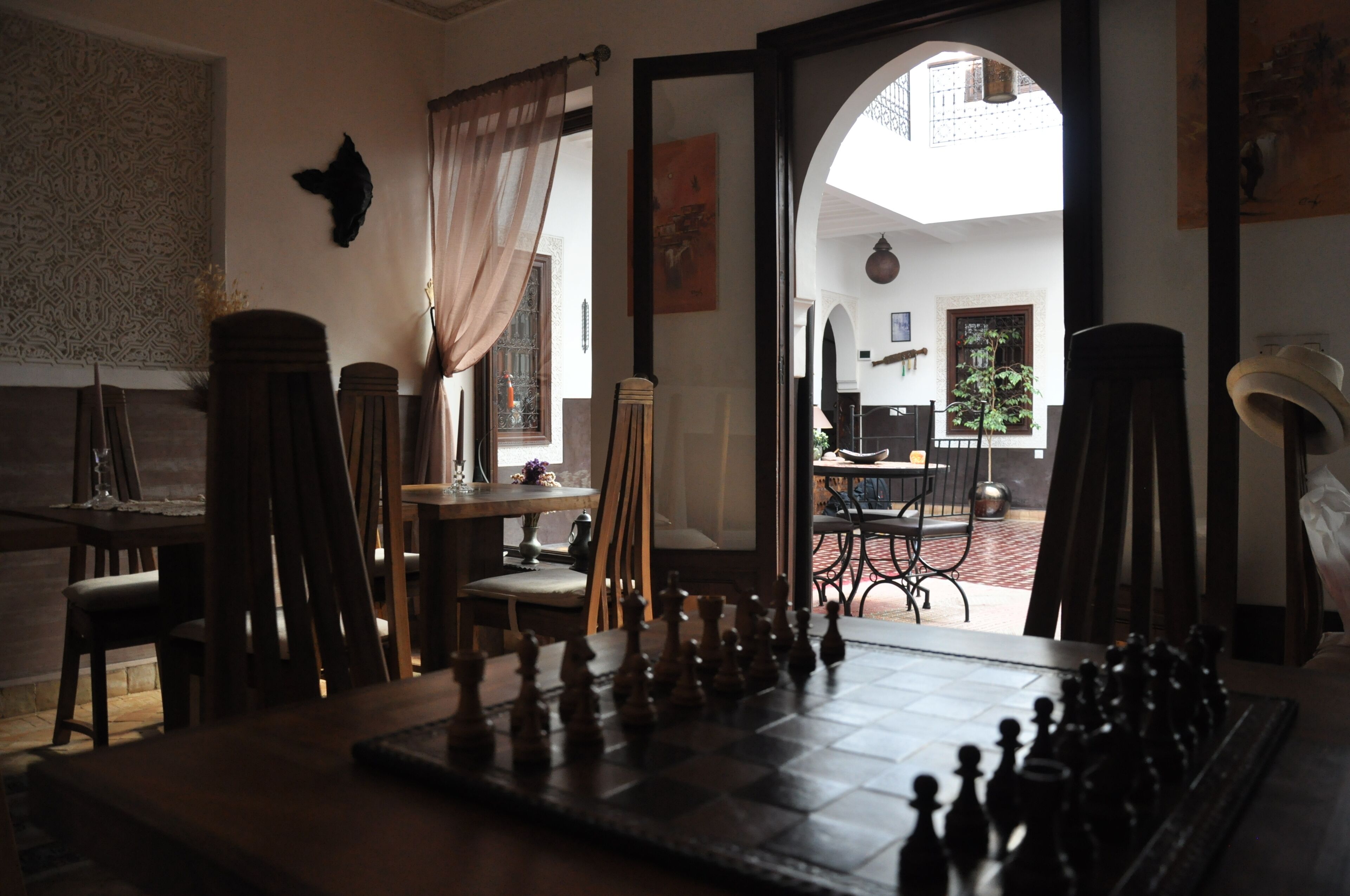Una habitación con un tablero de ajedrez, una mesa de comedor, sillas y vistas al exterior.