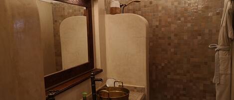 A bathroom with a large mirror, two sinks, a shower, and a tiled wall.
