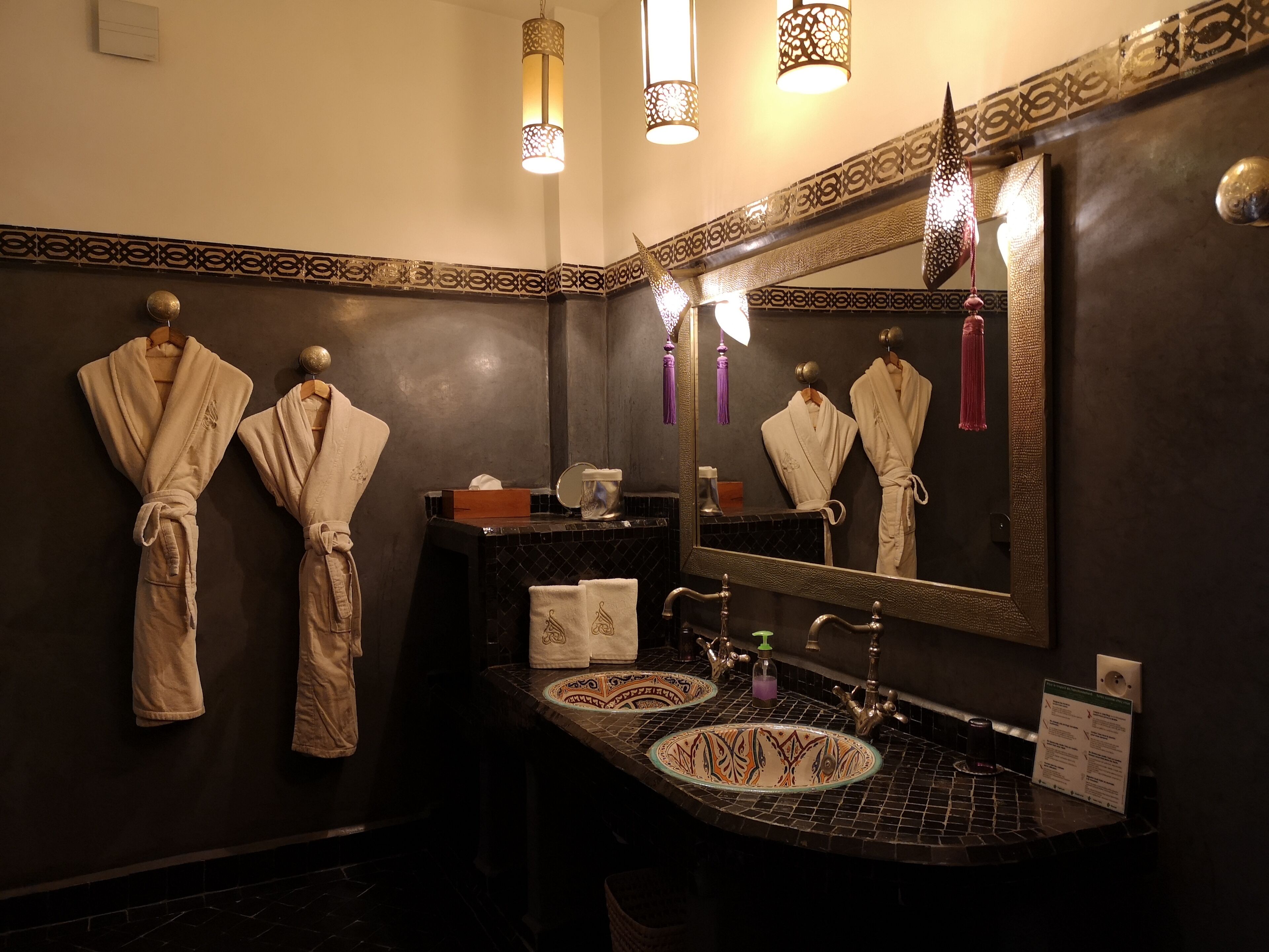 A bathroom with two sinks, a large mirror, and towels hanging on the wall.