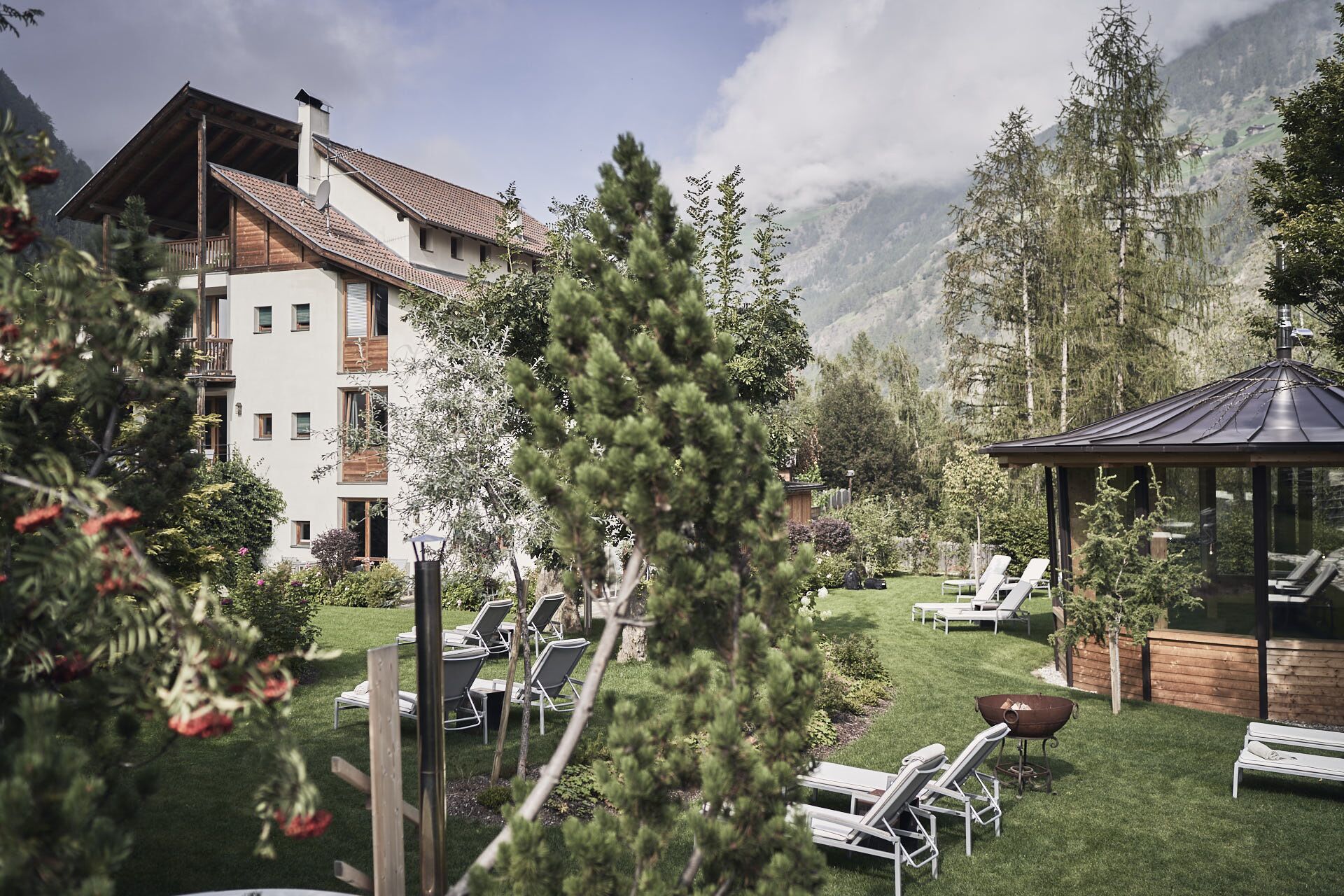 Ein Hotel mit Terrasse, Liegestühlen und Grillbereich.