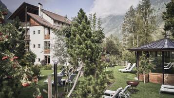 Ein Hotel mit Terrasse, Liegestühlen und Grillbereich.