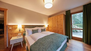 Una camera da letto con una testiera in legno, un letto con lenzuola bianche, un comodino e una finestra con tende.