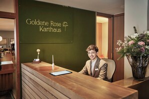 A reception desk with a wooden finish, a tablet, and a vase of flowers.