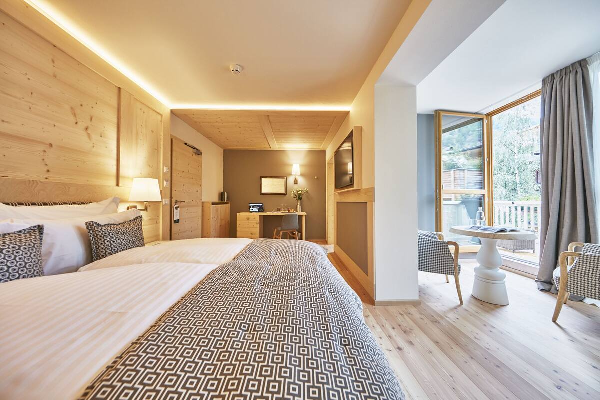 Une chambre d’hôtel avec un grand lit, un bureau et un balcon équipé de chaises.