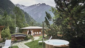 A hot tub, lounge chairs, a wooden deck, and a mountain backdrop. - Goldene Rose Karthaus (Senales)