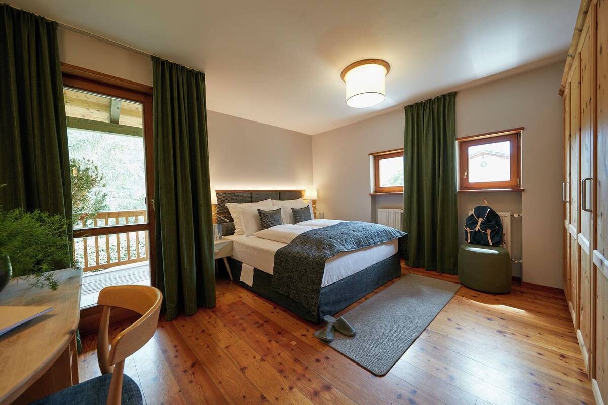 Une chambre à coucher avec un lit, un bureau, une chaise, une fenêtre et un radiateur.