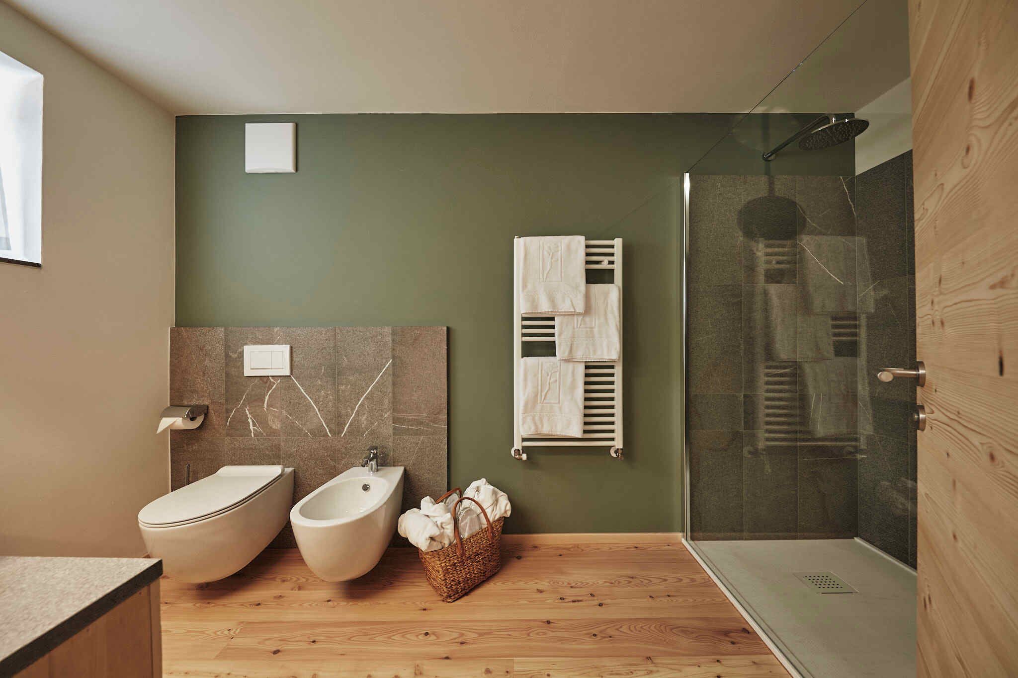 Ein modernes Badezimmer mit integriertem Bidet, Waschbecken, Duschkabine aus Glas und Holzboden.