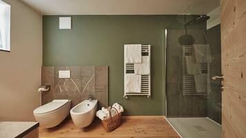 Ein modernes Badezimmer mit integriertem Bidet, Waschbecken, Duschkabine aus Glas und Holzboden.