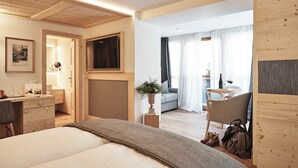 A hotel room with a bed, desk, chair, and a view of the living area. - Goldene Rose Karthaus (Senales)