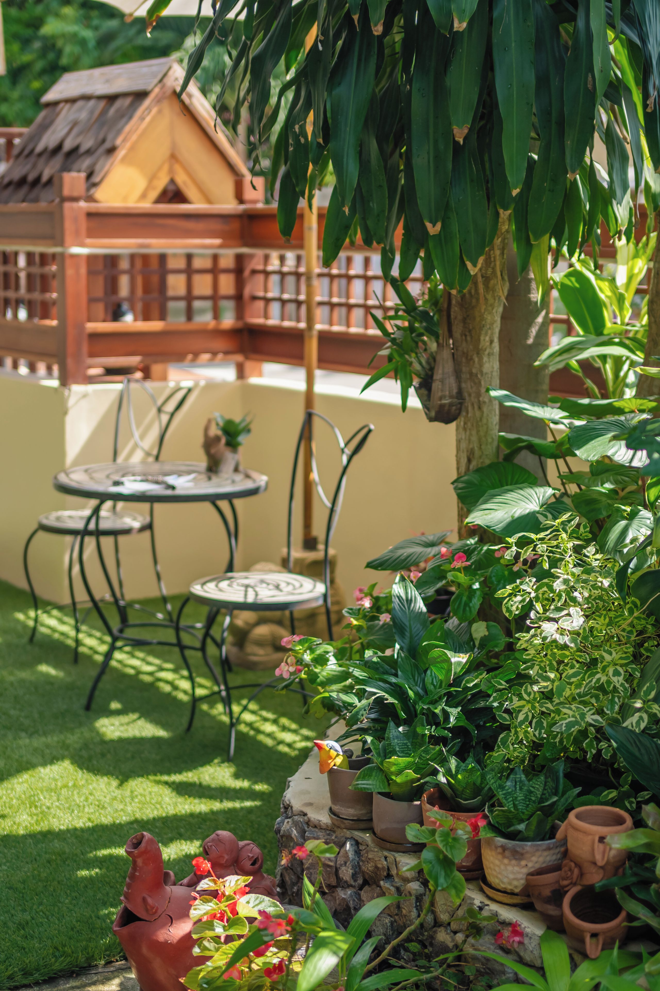 A patio with a table and chairs, surrounded by potted plants and a small garden.