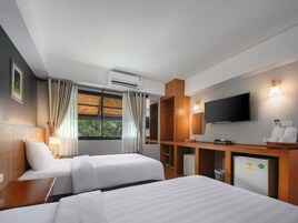 Une chambre d’hôtel avec deux lits, une télévision, un bureau et une armoire.