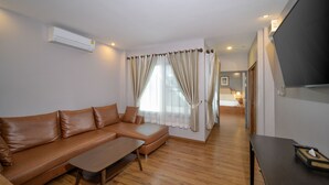 Una sala de estar moderna con un sofá de cuero, una mesa de centro de madera y un televisor de pantalla plana montado en la pared.