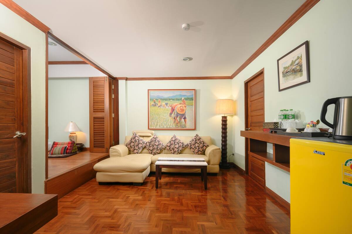 A living room with a sofa, a coffee table, a lamp, a painting, and a yellow refrigerator.