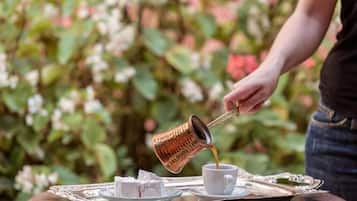 Una bandeja con una taza de café y un plato de pasteles, mientras una persona sirve café.