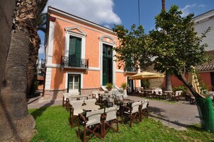 Un edificio con balcón, zona de estar al aire libre y un árbol.