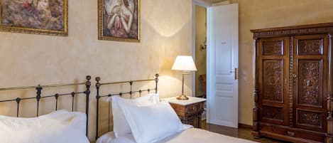 Une chambre d’hôtel avec un lit, une table de chevet, une lampe, une armoire et deux tableaux au mur.