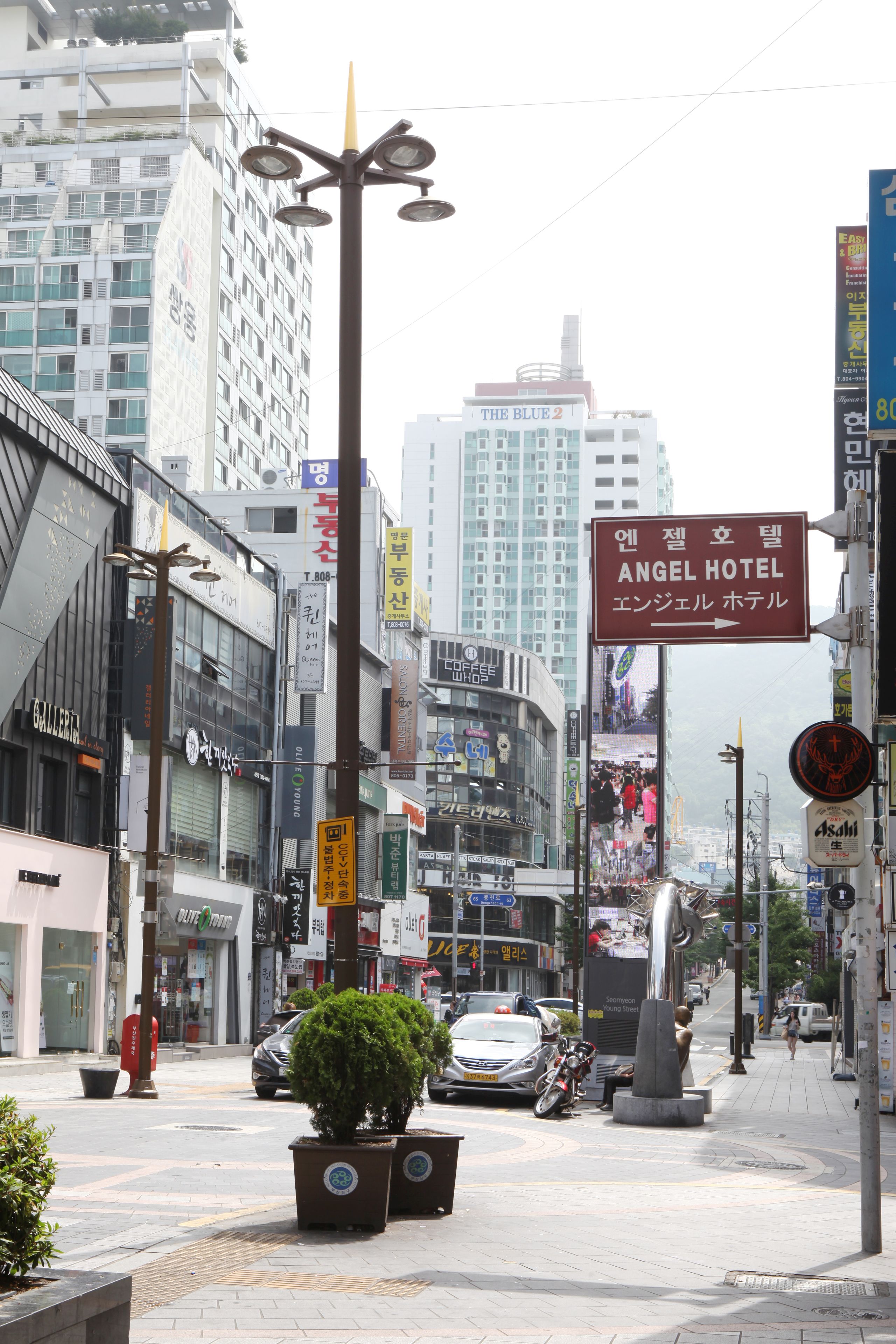 A busy urban street with a prominent hotel sign for the Angel Hotel.
