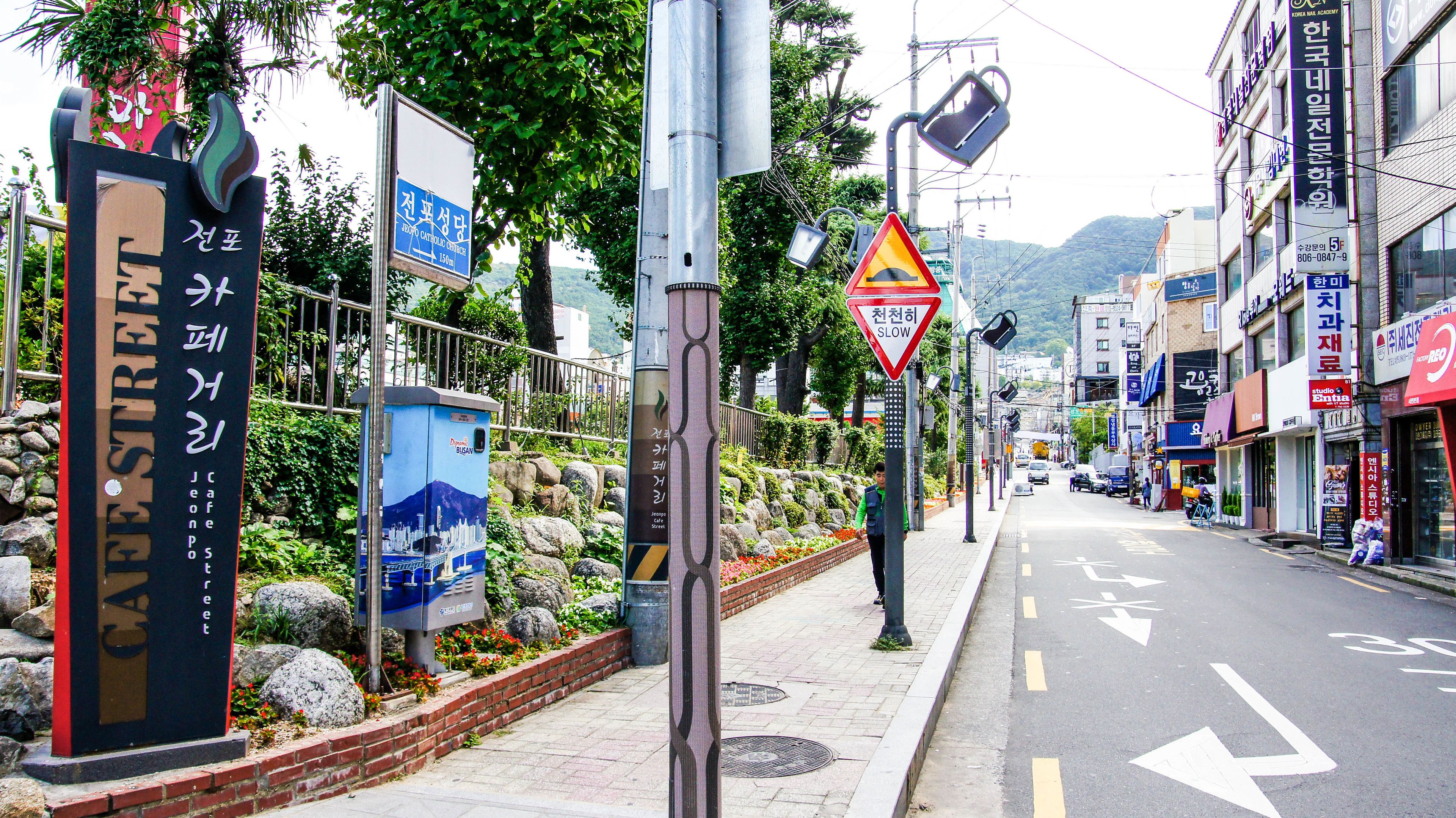 Une rue où l’on trouve des panneaux indiquant l’église catholique de Jeonpo et la zone de sécurité de Jeongpo.