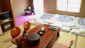 A traditional Japanese room with tatami flooring, a low wooden table with a kettle and tea set, a television, and a futon bed with patterned bedding. - Ryokan Kyo-no-yado Kagihei (Kyoto)