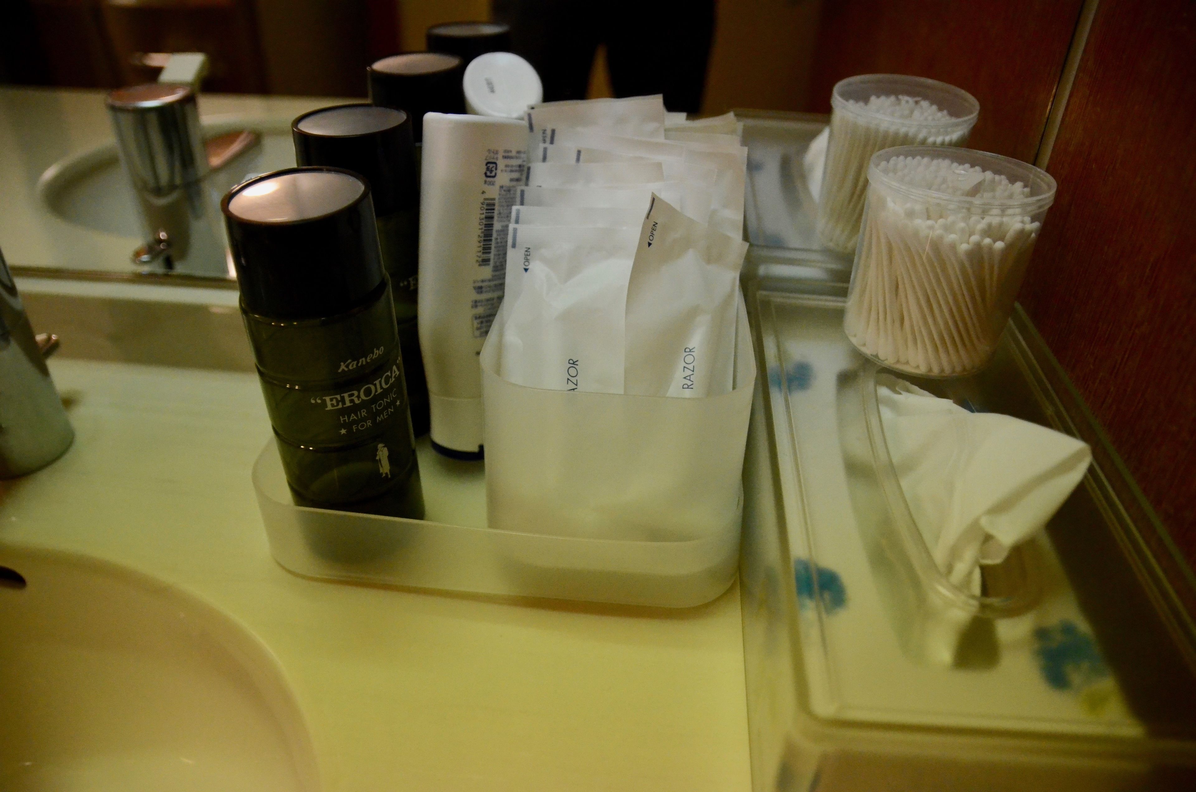 A bathroom counter with toiletries including a bottle labeled "Kanebo" and a tissue box.