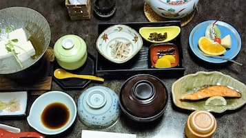 A dining table with various dishes, including fish, vegetables, and a teapot.