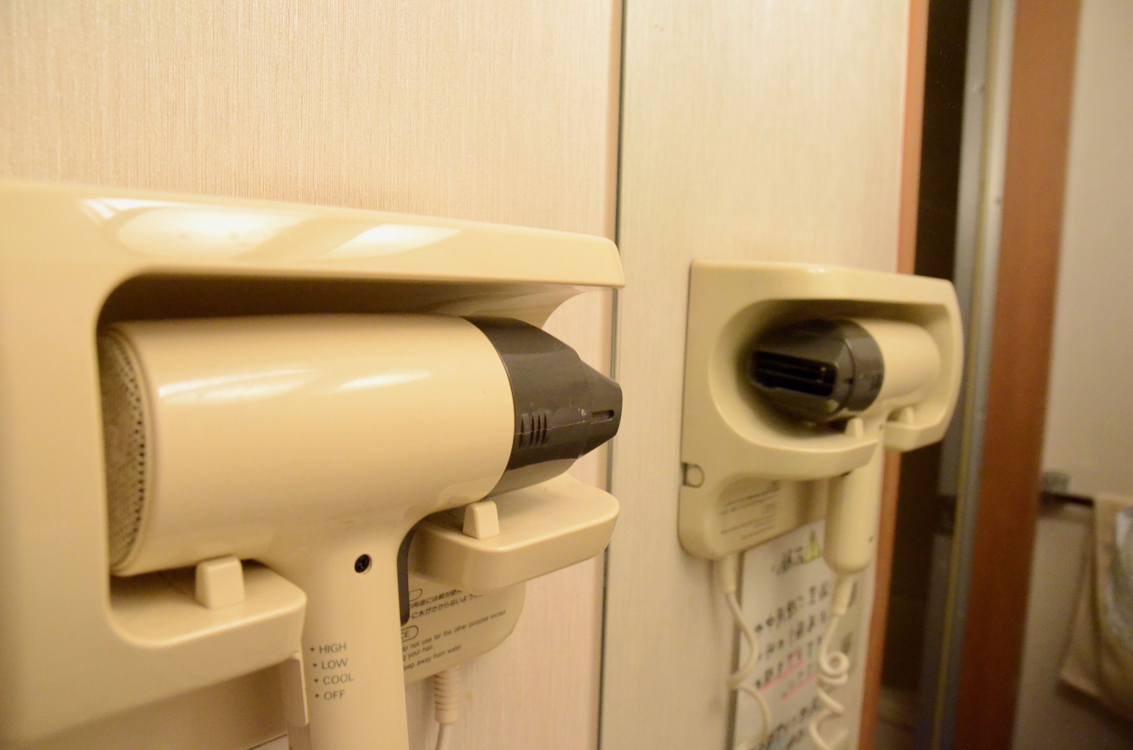 A hairdryer and a plug in a bathroom.